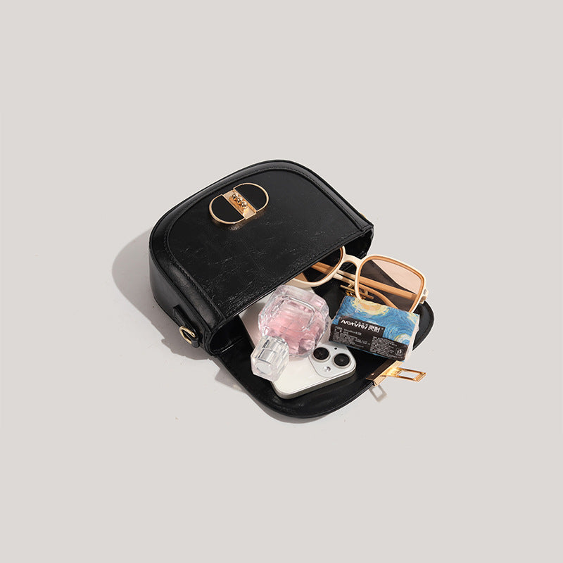 Black handbag with sunglasses, phone, and other items on a light gray background