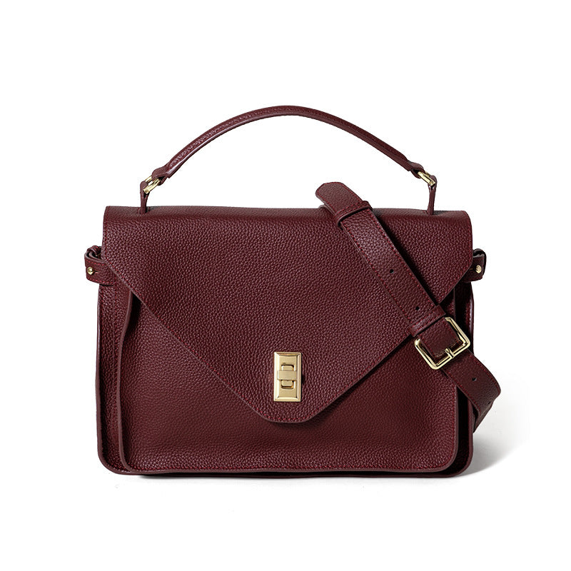 Brown leather handbag with gold clasp on a white background